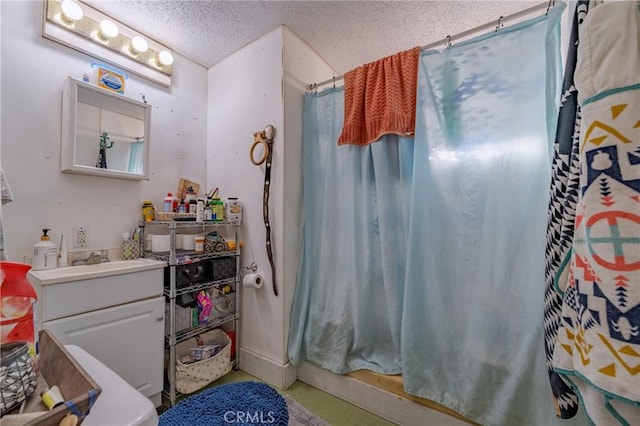 bathroom with a textured ceiling, curtained shower, and vanity