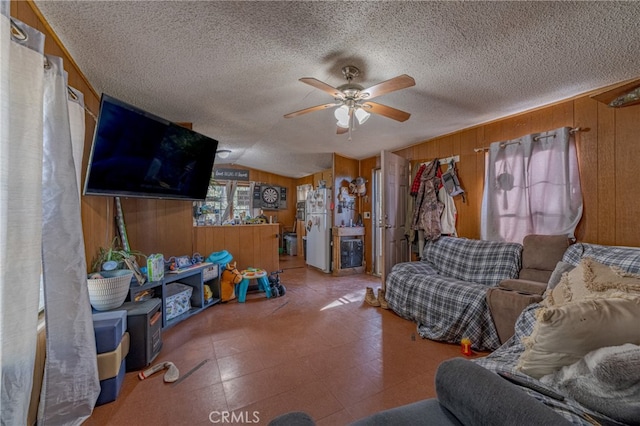 living room with wooden walls, vaulted ceiling, ceiling fan, and a textured ceiling