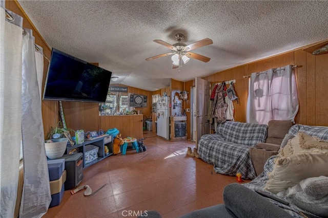 living area with tile patterned floors, wood walls, a ceiling fan, a textured ceiling, and lofted ceiling