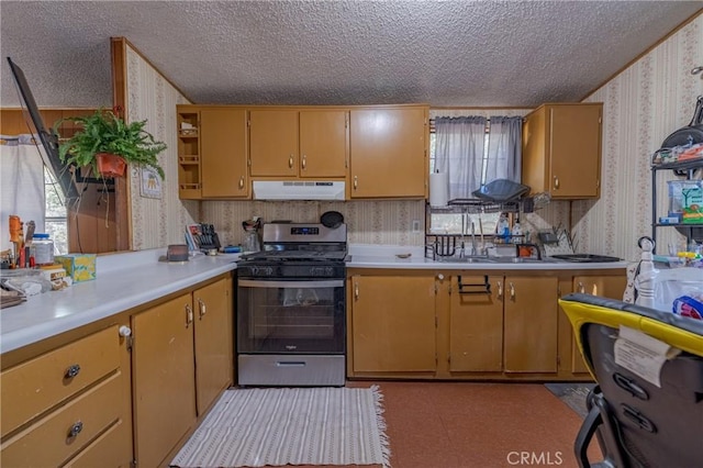 kitchen with wallpapered walls, stainless steel range with gas stovetop, a textured ceiling, and under cabinet range hood