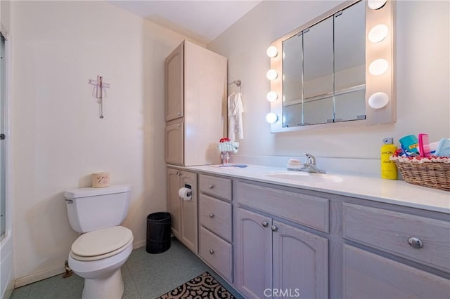 bathroom with toilet, vanity, shower / bath combination with glass door, and baseboards