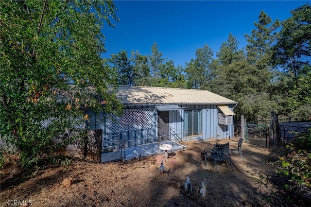 rear view of property with fence and metal roof