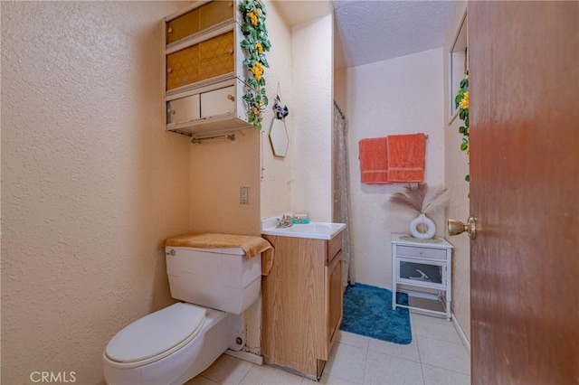 full bath with tile patterned floors, toilet, a textured wall, and vanity