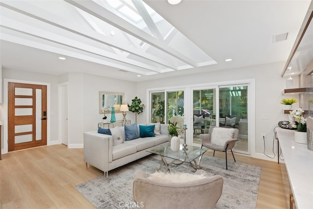 living room featuring a skylight and light hardwood / wood-style flooring