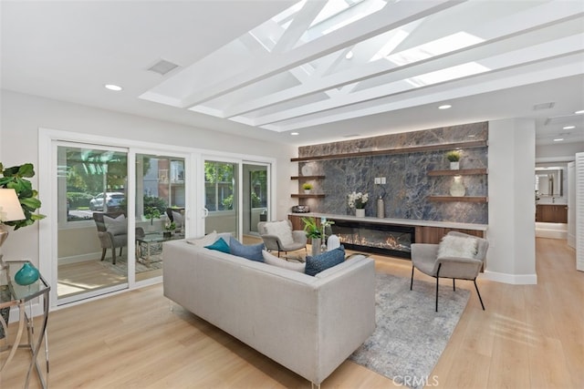 living room with a skylight, light wood-type flooring, and beam ceiling