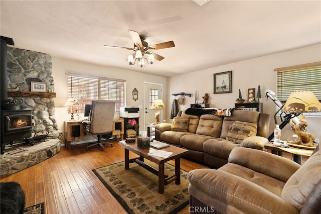 living room featuring hardwood / wood-style flooring, ceiling fan, and a wood stove