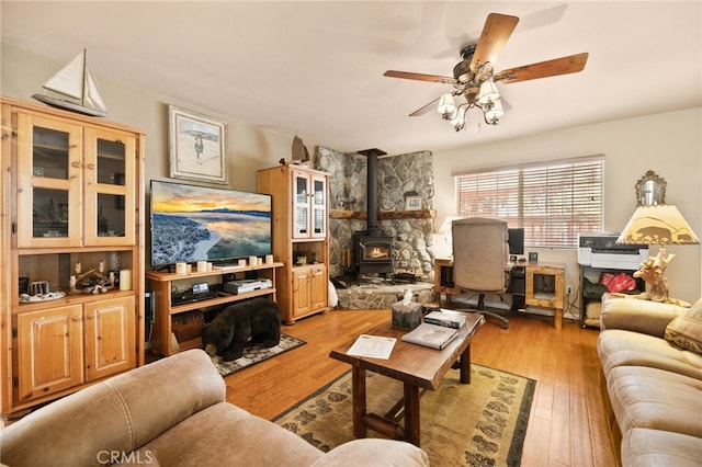 living room with ceiling fan, light wood-type flooring, and a wood stove