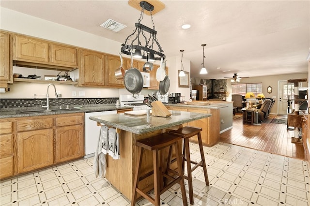 kitchen featuring pendant lighting, a center island, ceiling fan, light hardwood / wood-style floors, and a kitchen bar