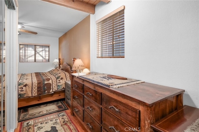 bedroom with ceiling fan, beamed ceiling, and wood-type flooring