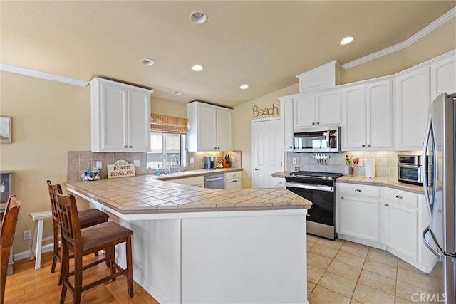 kitchen featuring kitchen peninsula, stainless steel appliances, and tile countertops