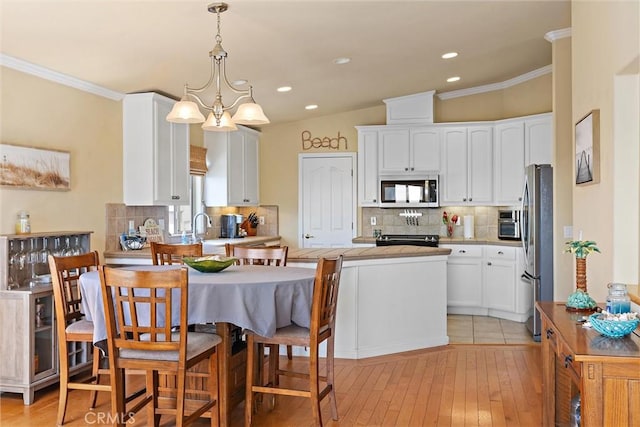 kitchen featuring white cabinetry, appliances with stainless steel finishes, decorative backsplash, a notable chandelier, and pendant lighting