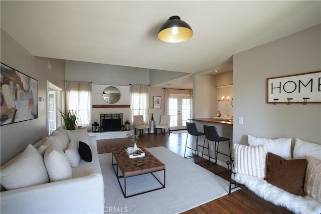 living room with a brick fireplace and dark wood-type flooring