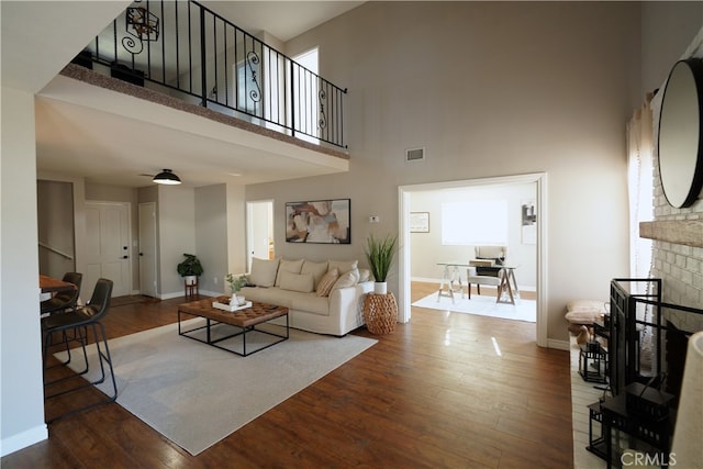 living room with wood-type flooring, a high ceiling, and a brick fireplace