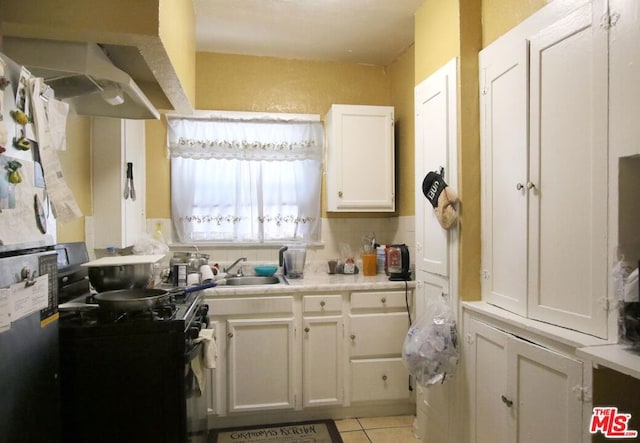 kitchen with black / electric stove, white cabinetry, sink, and light tile patterned flooring