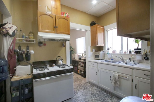 kitchen with white cabinetry, sink, light tile patterned floors, and white appliances