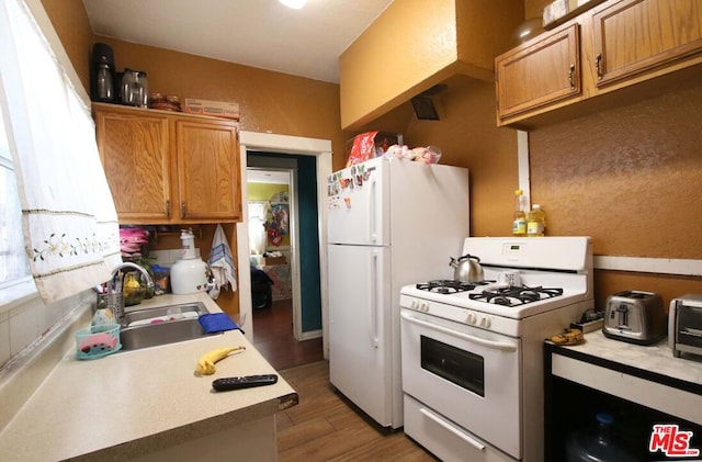 kitchen with dark hardwood / wood-style flooring, white appliances, and sink