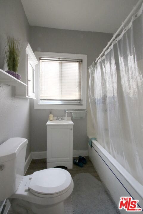 full bathroom featuring sink, toilet, shower / bathtub combination with curtain, and a baseboard heating unit