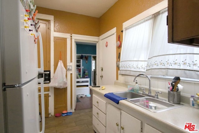 kitchen featuring white cabinetry, sink, light wood-type flooring, and white refrigerator