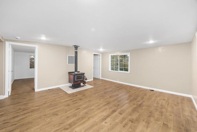 unfurnished living room featuring a wood stove and light hardwood / wood-style flooring