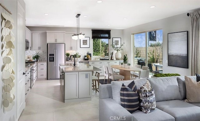 kitchen featuring open floor plan, light countertops, tasteful backsplash, decorative light fixtures, and stainless steel fridge with ice dispenser