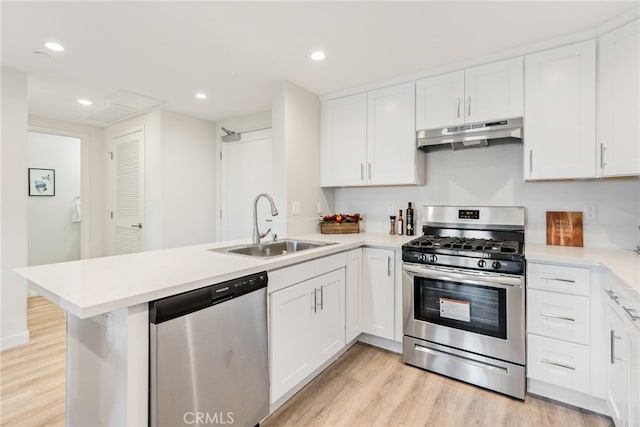 kitchen with appliances with stainless steel finishes, kitchen peninsula, white cabinetry, and sink