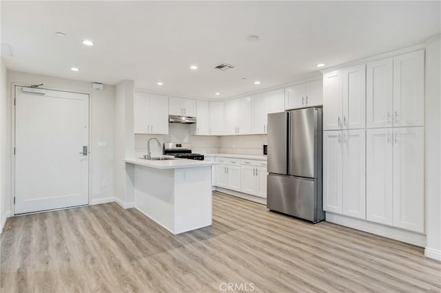 kitchen featuring white cabinets, stainless steel appliances, light hardwood / wood-style floors, and kitchen peninsula