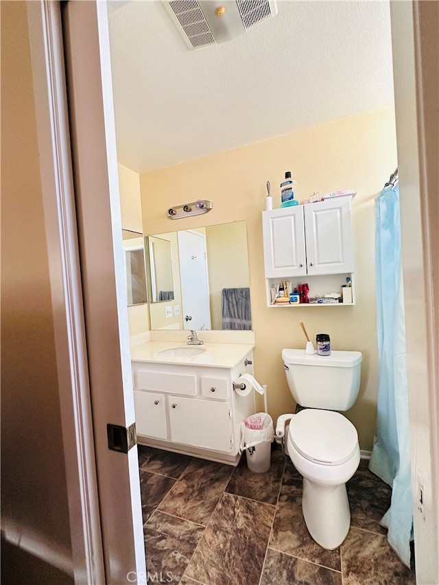 bathroom with toilet, walk in shower, and vanity