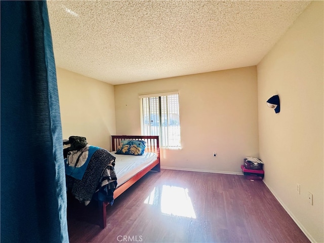 bedroom with dark hardwood / wood-style floors and a textured ceiling