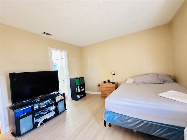 bedroom with a textured ceiling and light wood-type flooring