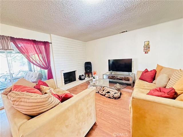 27358 Comwell St, Menifee, CA 92586 - living area featuring wood finished floors, a large fireplace, a textured ceiling, and visible vents