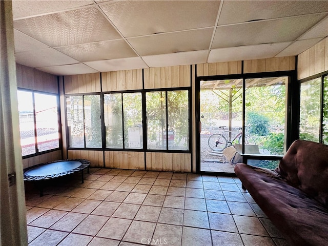 unfurnished sunroom with a drop ceiling and a healthy amount of sunlight