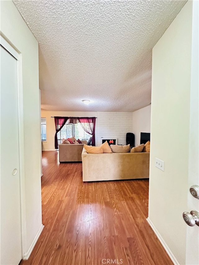 living room featuring a textured ceiling, light hardwood / wood-style flooring, and a fireplace