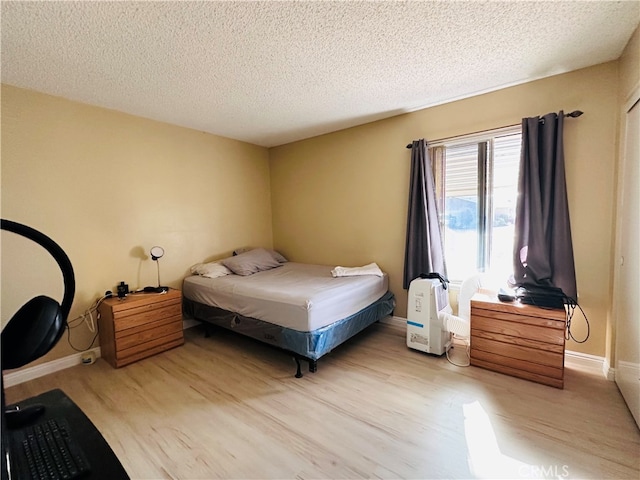 bedroom with a textured ceiling and light wood-type flooring