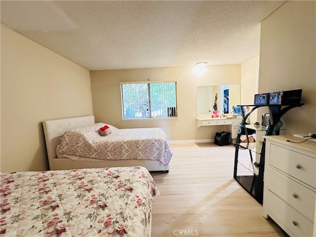 bedroom with light hardwood / wood-style floors and a textured ceiling