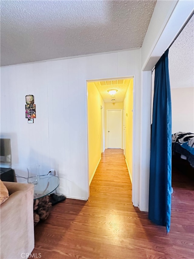 hall with hardwood / wood-style flooring and a textured ceiling