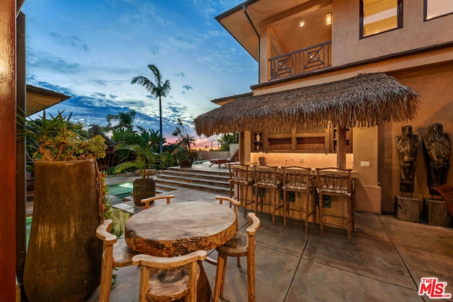 patio terrace at dusk with a balcony and a bar