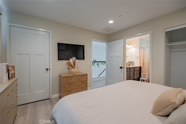 bedroom with a closet, light wood-type flooring, and ensuite bath