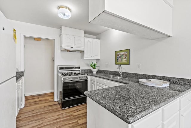 kitchen with white cabinets, gas range, kitchen peninsula, and sink