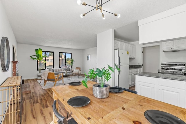 kitchen featuring dark hardwood / wood-style flooring, stainless steel gas range, an inviting chandelier, white cabinets, and white fridge