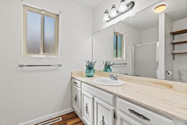 bathroom featuring wood-type flooring, vanity, toilet, and walk in shower