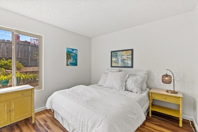 bedroom with a textured ceiling and dark hardwood / wood-style flooring