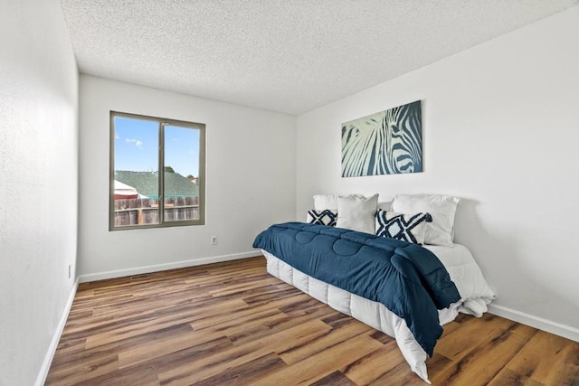 bedroom featuring a textured ceiling and hardwood / wood-style flooring