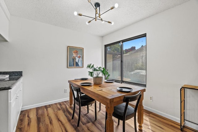 dining area featuring a chandelier, wood-type flooring, and a textured ceiling