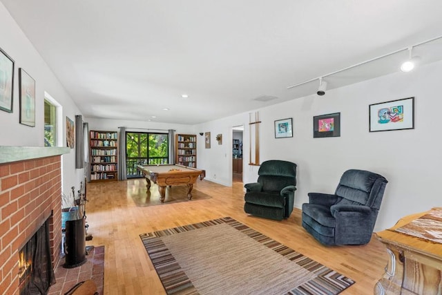 playroom with billiards, track lighting, a fireplace, and hardwood / wood-style floors