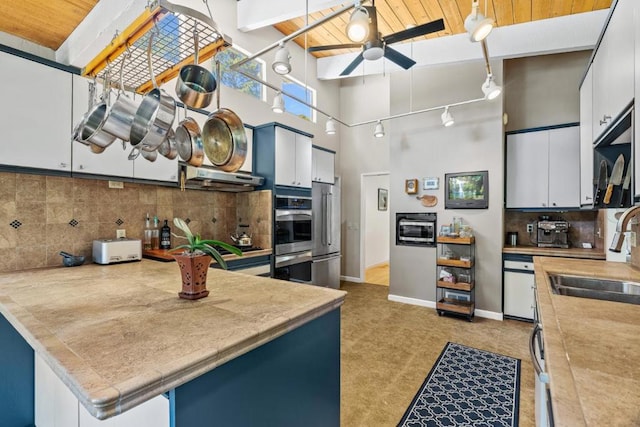 kitchen with white cabinets, a high ceiling, ceiling fan, decorative light fixtures, and sink