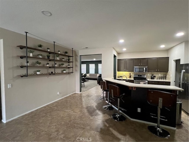 41097 Maiden Ct, Indio, CA 92203 - kitchen with stainless steel appliances, light countertops, a kitchen breakfast bar, decorative backsplash, and tile patterned floors