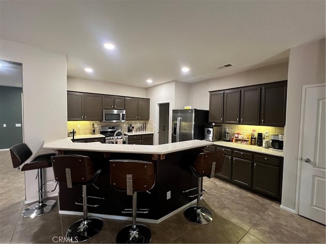 41097 Maiden Ct, Indio, CA 92203 - kitchen featuring appliances with stainless steel finishes, a breakfast bar area, tasteful backsplash, light countertops, and recessed lighting
