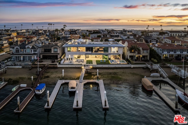 aerial view at dusk featuring a water view