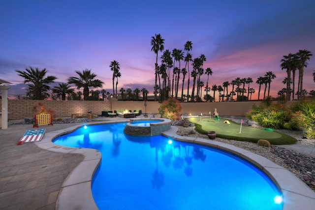 pool at dusk with a patio and an in ground hot tub