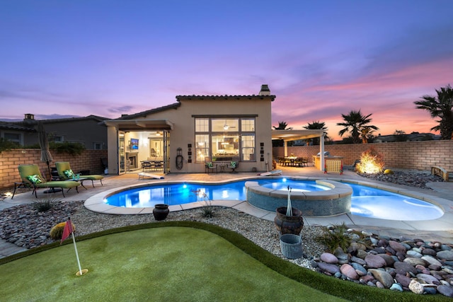 pool at dusk featuring an in ground hot tub and a patio area